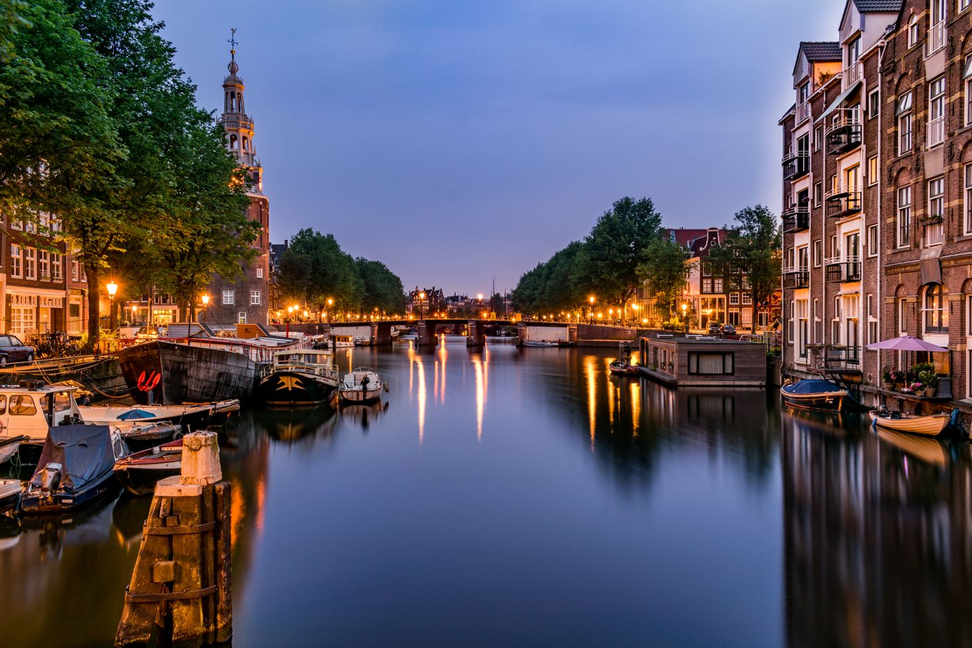 Amsterdamse gracht met verlichte grachtenpanden in de avond