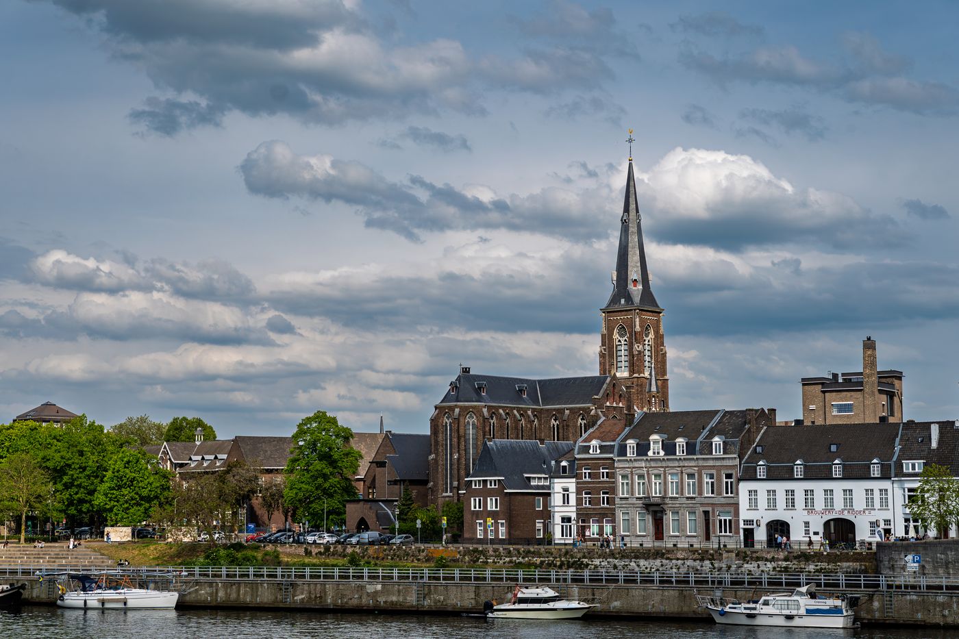 Historische huizen en een kerktoren aan de Maas in Maastricht